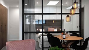 Une chambre d’hôtel moderne dotée d’une grande fenêtre, d’un coin repas avec une table et des chaises, et d’un lit offrant une vue agréable.