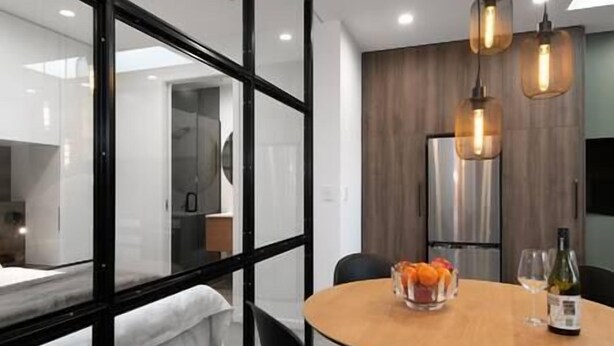 Une chambre d’hôtel moderne dotée d’une table de salle à manger ronde, d’un réfrigérateur et d’une cloison en verre.