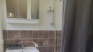 Une salle de bain avec un lavabo blanc, une baignoire et une douche.