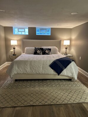 A neatly arranged bedroom with a large bed, two bedside tables with lamps, a patterned rug, and a window with a view. - Cozy & Modern 3-Bed Getaway Near Lake Erie (Bay Village)
