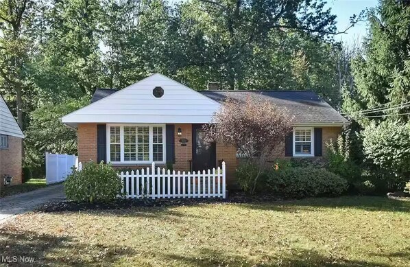 A single-story house with a gabled roof, a front porch, and a white picket fence. - Cozy & Modern 3-Bed Getaway Near Lake Erie (Bay Village)