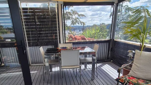Un espace extérieur abrité, aménagé avec une table et des chaises, un pot de fleurs et offrant une vue sur le paysage environnant.