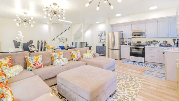 A modern living room with a sectional sofa, a dining area, and a kitchen with stainless steel appliances. - J. Lovely & Spacious 3BR Home by Universal with Patio + Parking (Los Angeles)