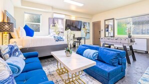 A modern hotel room with a bed, blue sofas, a foosball table, and artwork on the walls. - J. Lovely & Spacious 3BR Home by Universal with Patio + Parking (Los Angeles)