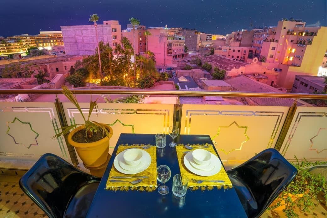 A dining table set for two with a city view at night.
