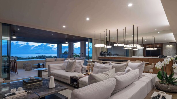 A modern living room with a large sofa, a coffee table, and a view of the ocean. - Marea Surf Residences: 4BR, Private Pool & Golf Cart (Punta Mita)