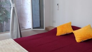 Quarto com cama grande, janela com cortinas e vista para o exterior.