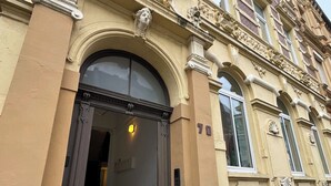 Rakennuksessa on suuri kaarimainen sisäänkäynti, portaikko, joka johtaa sisäänkäyntiin, ja julkisivussa on numero 70.
