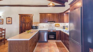 A kitchen with wooden cabinets, a built-in oven, a dishwasher, and a refrigerator. - El Acebuche Mijas by Ruralidays (Málaga)