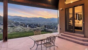 Un patio con mesa y sillas que ofrece vistas panorámicas de montañas y un valle.