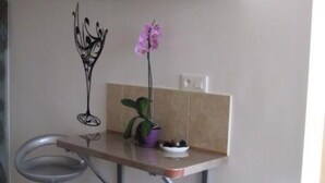 Een kleine kitchenette met twee barkrukken, een potorkidee en een wandairconditioner.