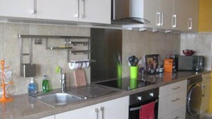Een moderne keuken met witte kasten, een roestvrijstalen afzuigkap, een inbouwoven, een magnetron en een vaatwasser.