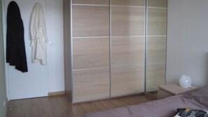 Een slaapkamer met een kledingkast, een bed en een nachtkastje.