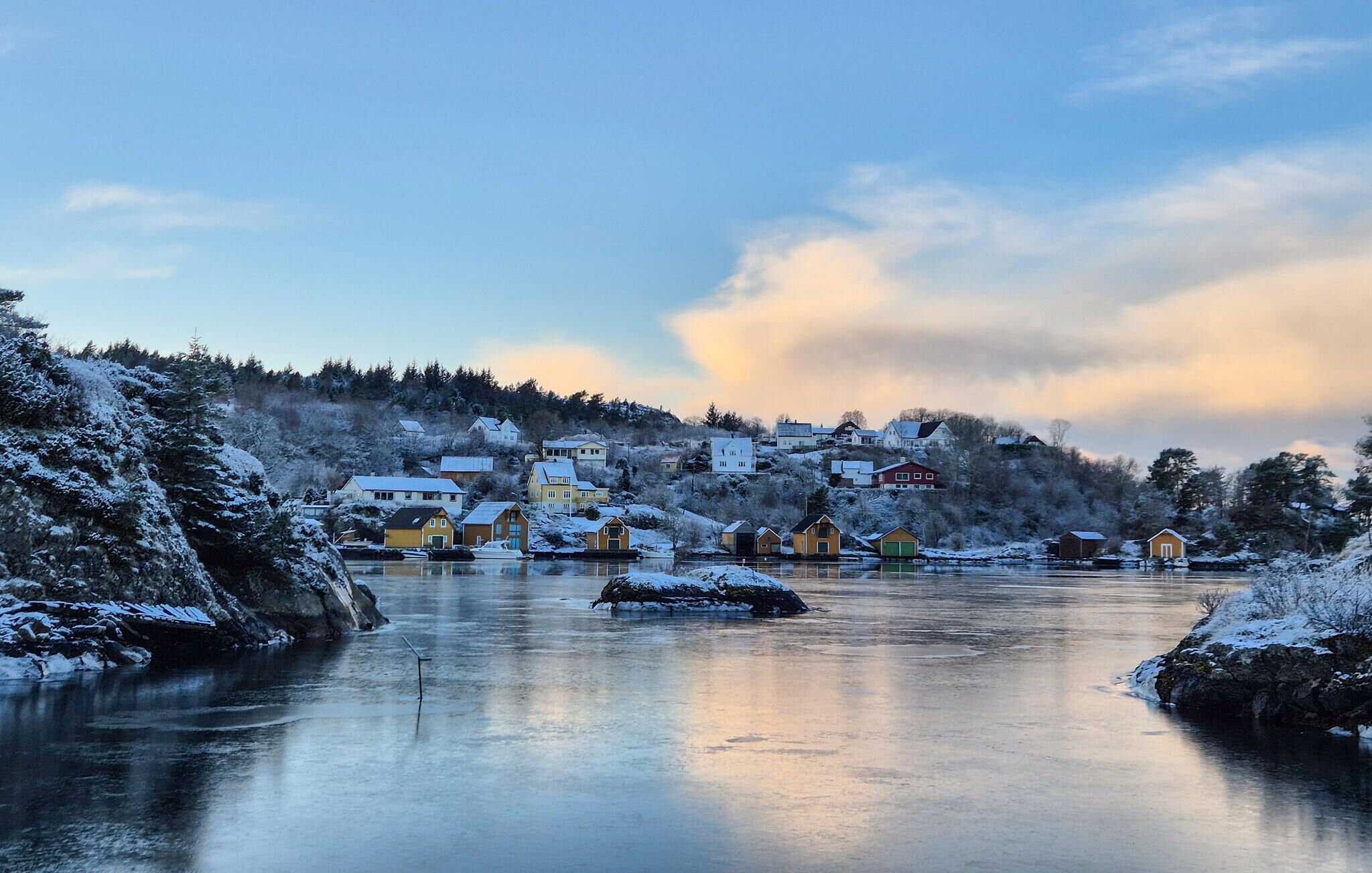 Ein idyllisches Flussdorf mit schneebedeckten Häusern und einem ruhigen Fluss.