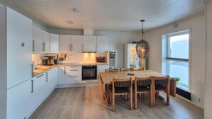 A modern kitchen with white cabinets, a wooden dining table, and a large window. - Stunning apartment in Finnås with house sea view (Finnås)