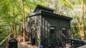 Une terrasse en bois avec des meubles d’extérieur, un barbecue et un espace salon abrité.