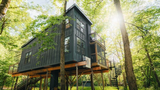 Une cabane dans les arbres à plusieurs niveaux, dotée de rampes en bois et d’un escalier.