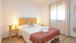 A hotel room with a bed, two bedside tables with lamps, a window with curtains, and a wooden floor. - El Moral Prado del Rey by Ruralidays (Cádiz)