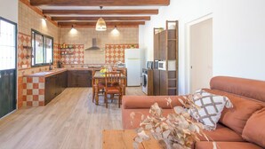 A kitchen with a dining area, wooden cabinets, a built-in oven, and a refrigerator. - El Moral Prado del Rey by Ruralidays (Cádiz)