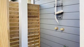A wooden gate leading to a grey exterior wall with a showerhead mounted on it. - Saltwater Solace, For 8-FREE WIFI/FREE PARKING/FREE BEACH ACCESS (Galveston)