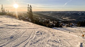 Ein verschneiter Ski-Hang mit deutlichen Spuren und eine Stadt im Tal darunter.