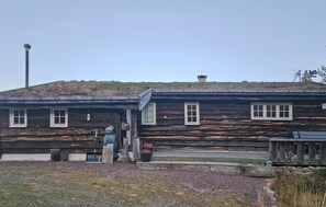 Eine rustikale Blockhütte mit geneigtem Dach, einem Schornstein und einer kleinen Veranda.
