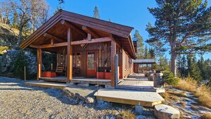 A wooden cabin with a sloped roof, a covered porch, and a ski rack. - Stunning home in Austbygda with WiFi (Austbygda)