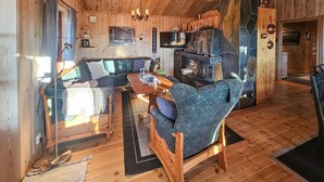 A cozy cabin interior with a wooden dining table, a sofa, and a stone fireplace. - Stunning home in Austbygda with WiFi (Austbygda)