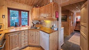 A wooden kitchen with a large window, wooden cabinets, and a dishwasher. - Stunning home in Austbygda with WiFi (Austbygda)