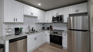 A modern kitchen with white cabinets, stainless steel appliances, and a granite countertop. - Relaxing ATL Getaway • Modern, Clean & Near City Events, Stadiums, & Attractions (Atlanta)
