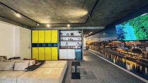 A modern interior with a sofa, yellow lockers, a kitchenette, and a cityscape mural. - Circel of 2 (Belgrade)