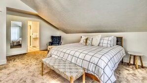 Une chambre à coucher avec un grand lit, un banc, une chaise et une petite table.