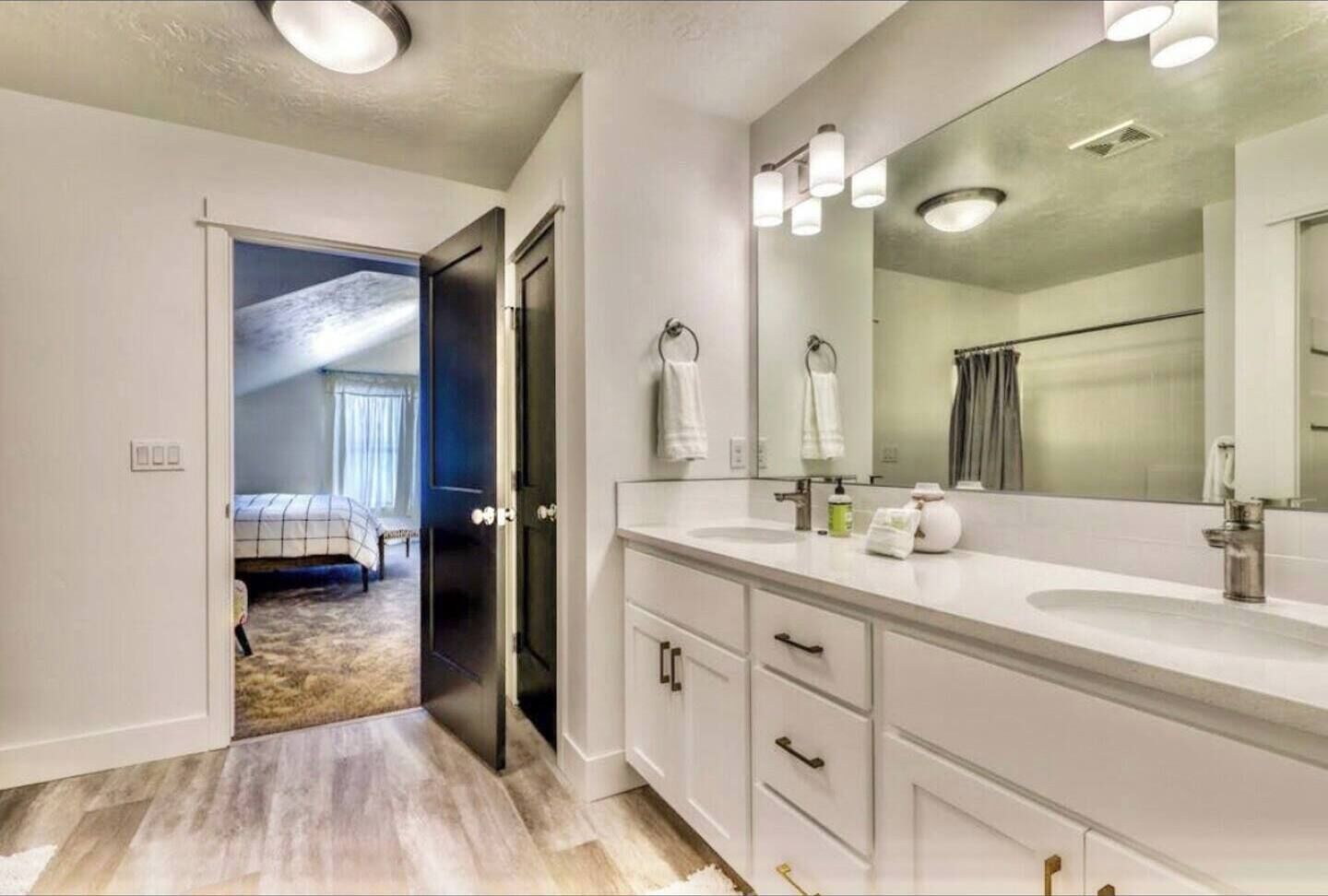 Een moderne badkamer met een grote spiegel, twee wastafels en een inloopdouche.