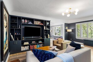 A modern living room with a dark-colored entertainment unit, a flat-screen TV, a sofa, and a coffee table.
