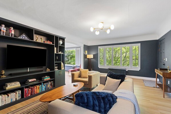 A modern living room with a large flat-screen TV, a bookshelf, a sofa, and a coffee table.