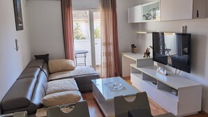 A modern living room with a sofa, coffee table, and TV. - Studio Dunja (Niksic)
