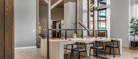 A modern office space with a long table, four chairs, and a potted plant.