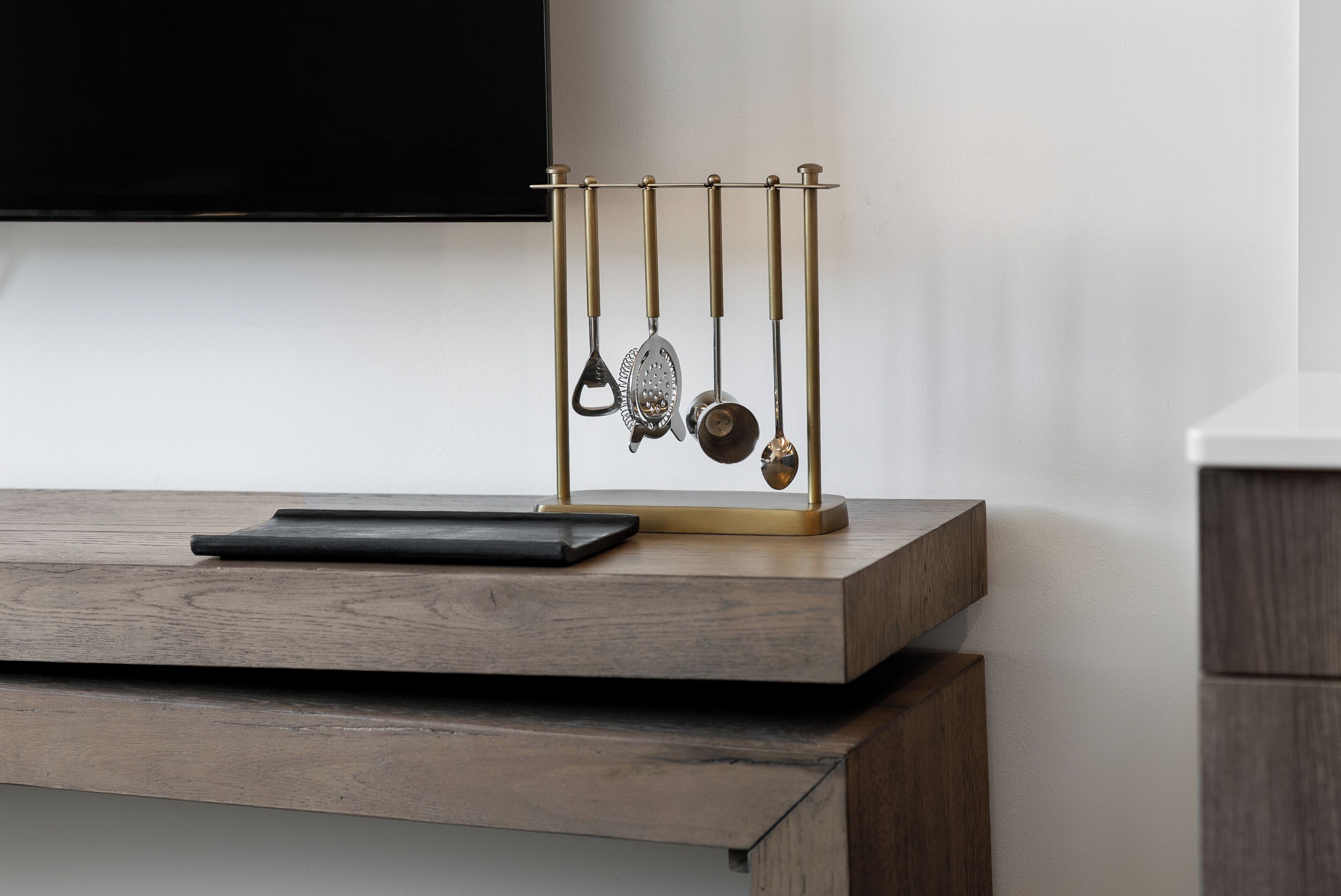 A kitchen counter with a utensil holder and a black tablet.