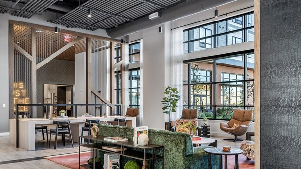 Un interior amplio y moderno con una zona de estar central, una cocina y ventanas grandes que ofrecen vistas al exterior.