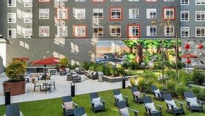 Un patio de hotel con asientos exteriores, sillones de descanso y un mural de un árbol.