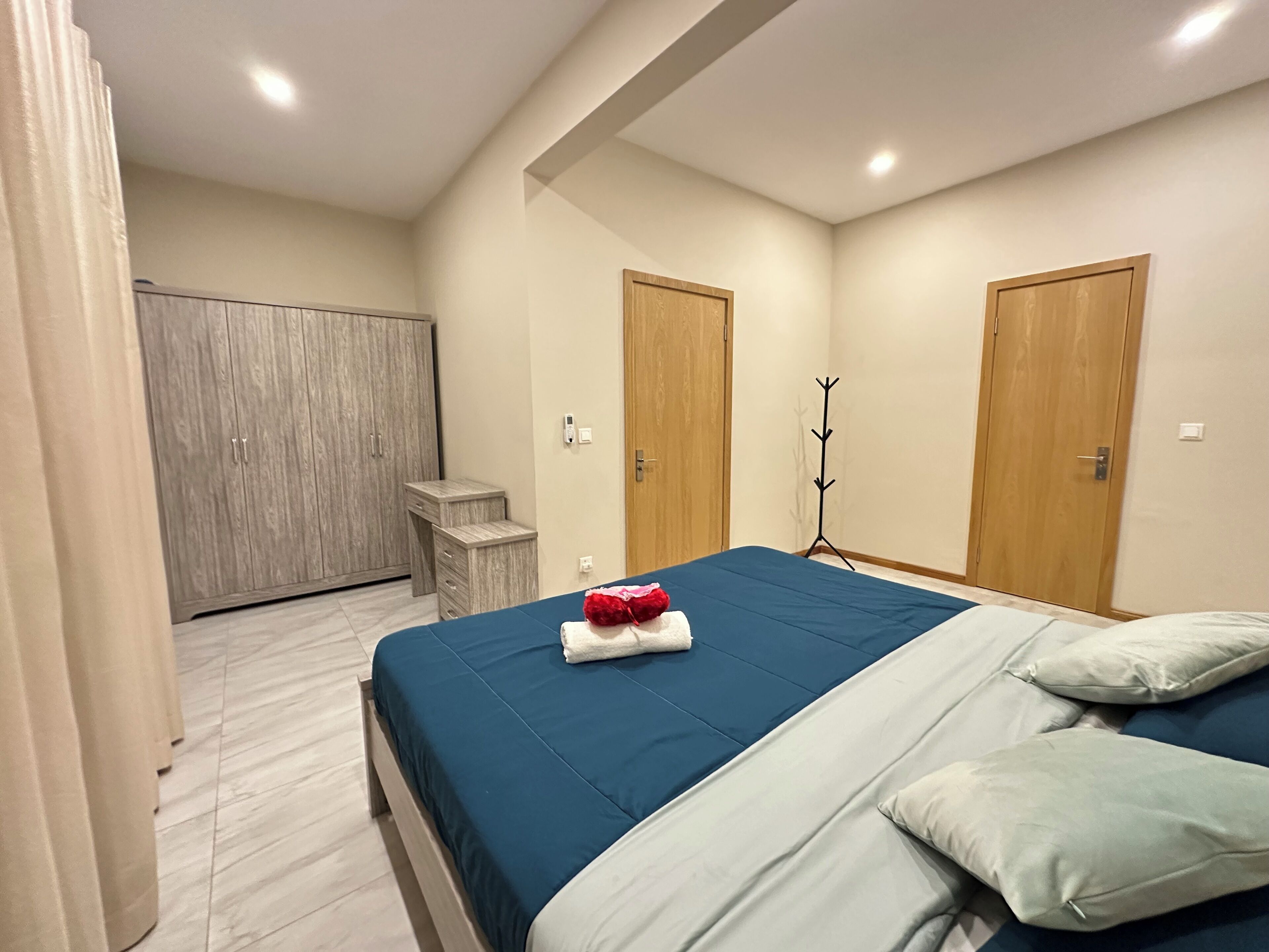 Une chambre à coucher avec un lit, deux portes en bois, un porte-manteau et une armoire.