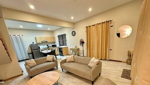 Ein geräumiges Wohnzimmer mit zwei Sofas, einem runden Couchtisch und einer Küche im Hintergrund.