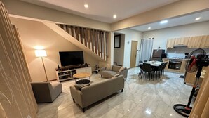 Ein modernes Wohnzimmer mit Sofa, Fernseher und Essbereich.