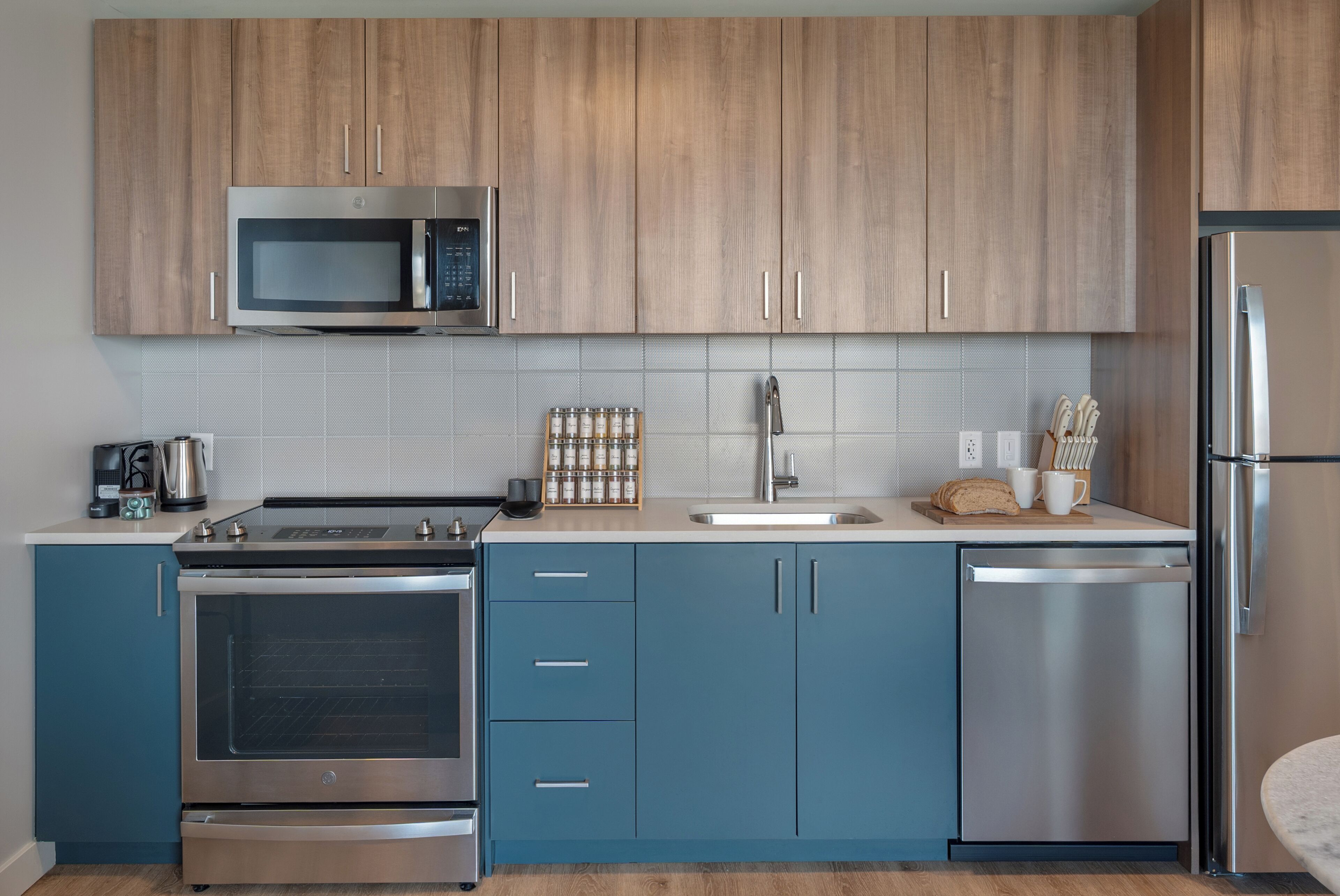 A modern kitchen with stainless steel appliances, wooden cabinets, and a blue countertop.