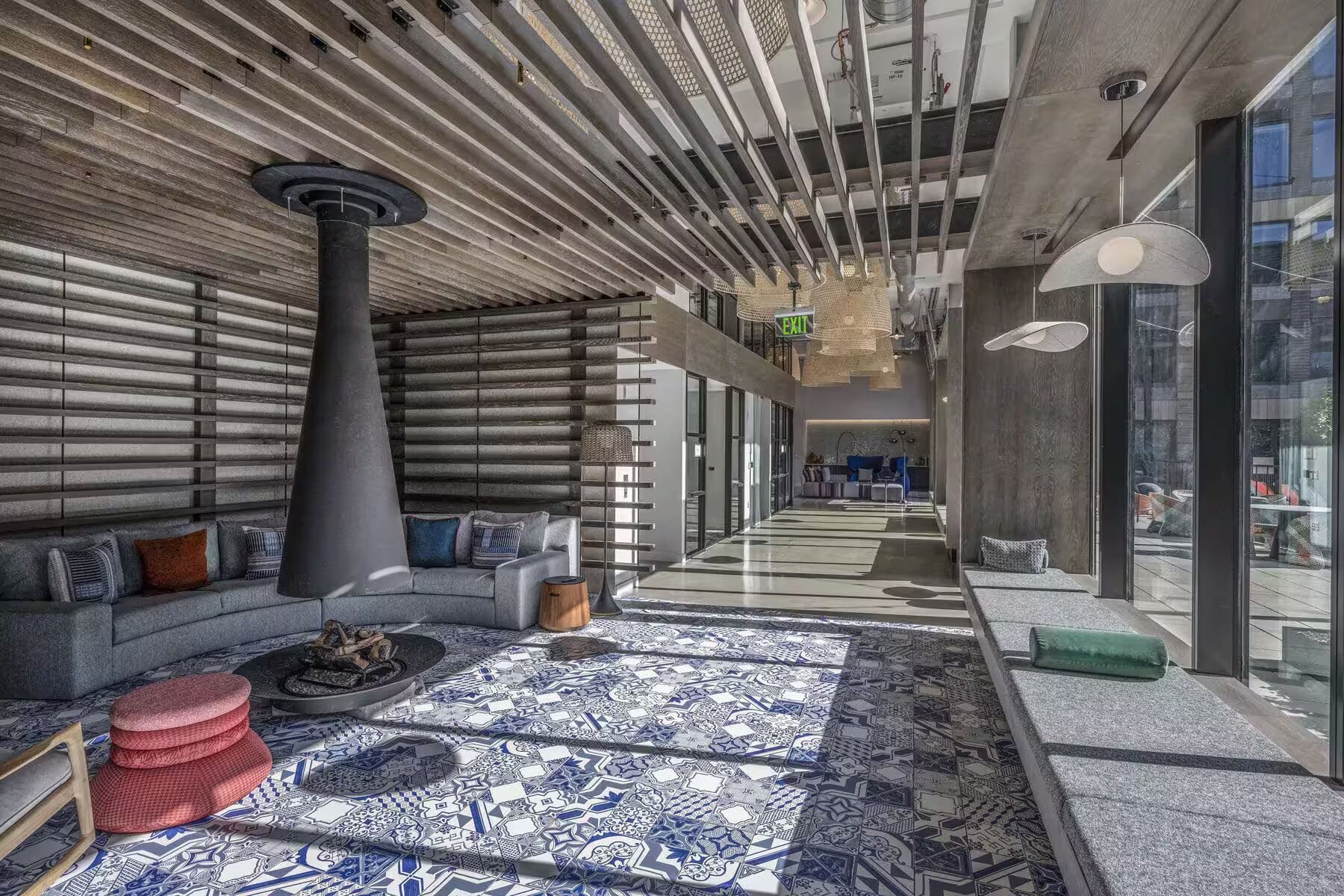 Un hall d’entrée moderne avec un sol à motifs, une grande colonne et un canapé agrémenté de coussins.