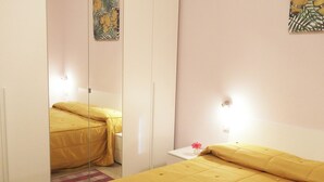 A bedroom with a bed, a nightstand, a mirror, and a wall-mounted light.