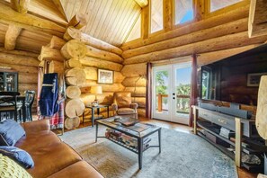 A log cabin interior with a sofa, coffee table, TV, and a fireplace. - Lakeside Log Cabin. Hot tub, Dock, Boat Lift! (Manning)