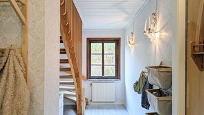 A narrow hallway with a wooden staircase, a radiator, and a window with a view of trees. - Cozy home in Ystad with sauna (Ystad)