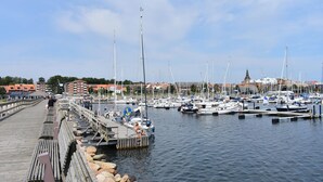 A marina with boats docked, a wooden pier, and buildings in the background. - Cozy home in Ystad with sauna (Ystad)