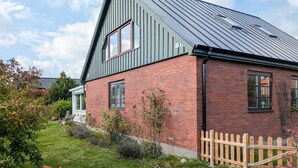 A two-story house with a sloped metal roof, brick walls, and a wooden fence. - Cozy home in Ystad with sauna (Ystad)